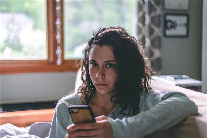 Traurige Frau mit Handy starrt in die Kamera
