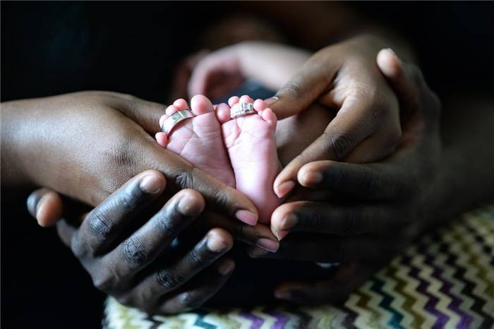 Ein Paar, das die Füße seiner Kinder mit den Händen umarmt