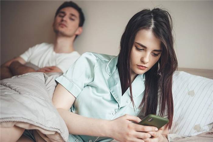 Mädchen mit Telefon und Mann im Bett