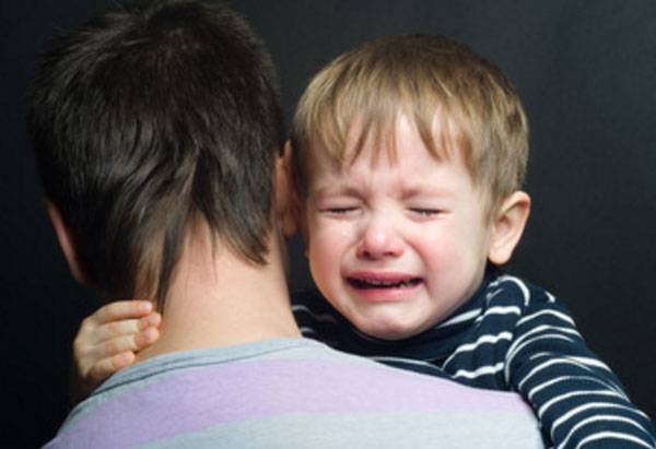 Ein Baby weint in Papas Armen.