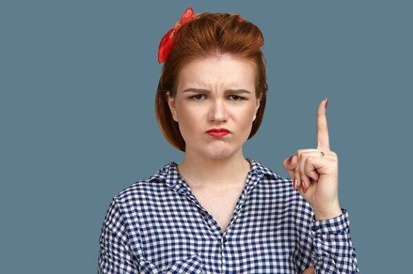 Verärgerte Frau hält den Finger hoch und ermahnt ihren Mann