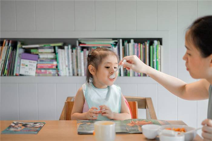 Mutter, die ihre Tochter mit dem Löffel füttert