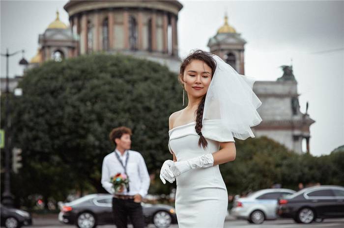Braut im weißen Kleid mit Bräutigam, Autos und Stadtlandschaft im Hintergrund