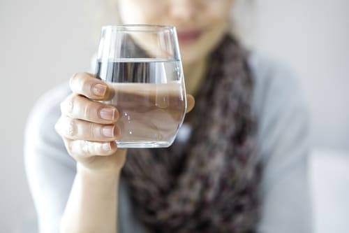 Ein Glas Wasser in der Hand