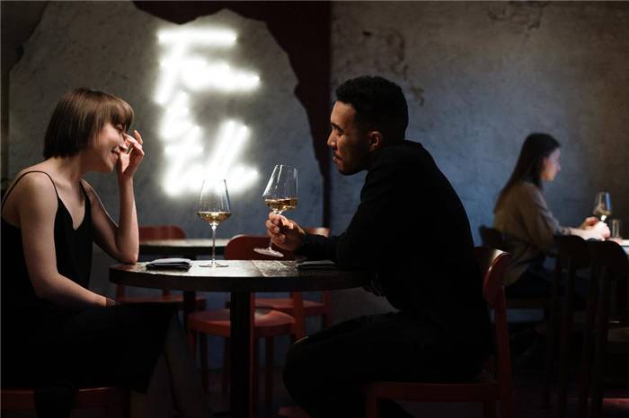 Ein Mann und ein Mädchen sitzen mit einem Glas Wein an einem Tisch in einem Restaurant.
