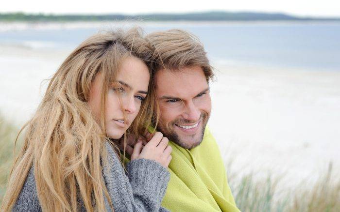 Ein Mädchen in einer grauen Jacke sitzt neben einem Mann.