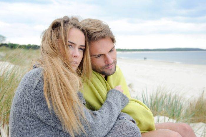Mädchen in grauer Jacke umarmt einen Mann.